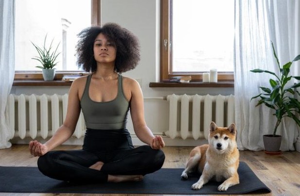 a woman practicing yoga with her dog
